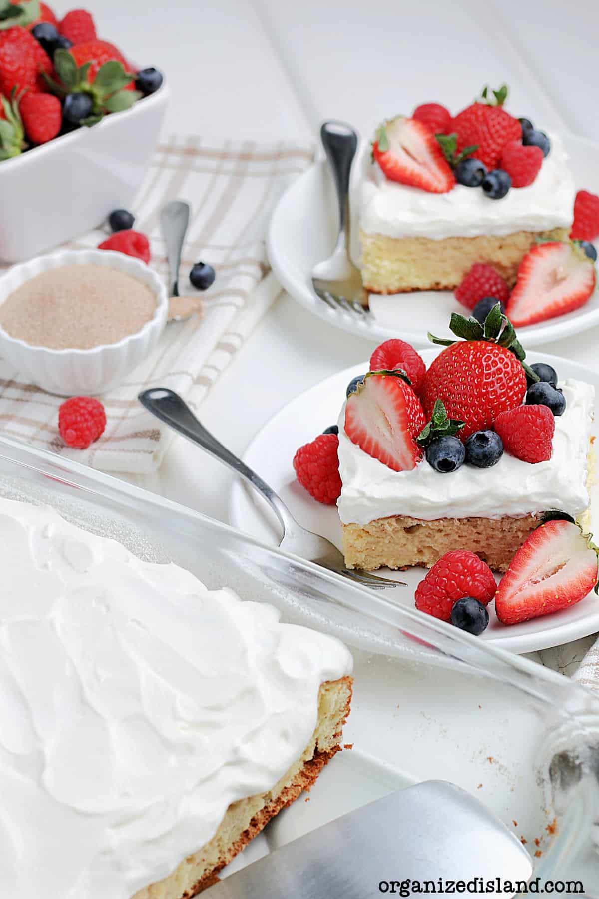 Tres Leches Cake with Strawberries and Blueberries, sliced on plates.