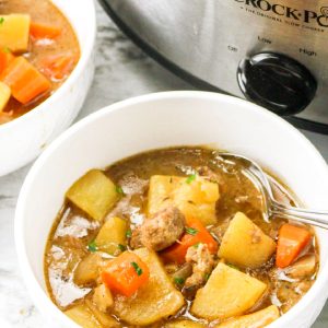 Slow Cooker Irish Beef stew in bowl next to slow cooker.