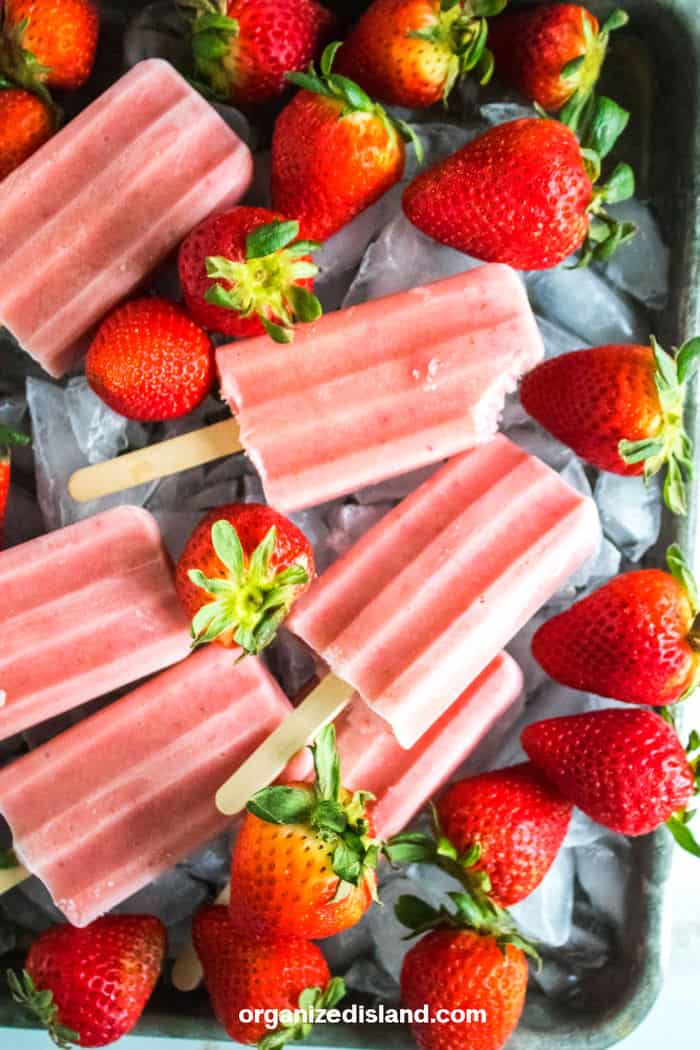 Strawberry Banana Popsicles with strawberries on ice.