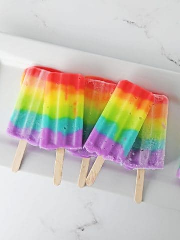 Homemade Rainbow Popsicles on plate.