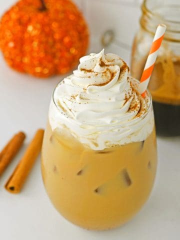 Iced Pumpkin Spice Latte in glass with whipped cream.