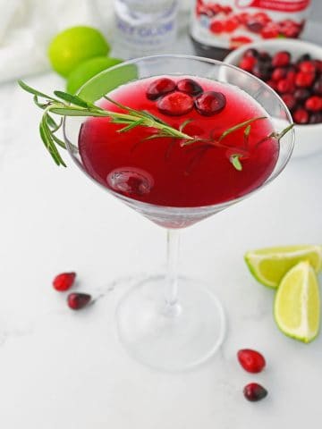 Mistletoe Martini in glass with cranberries.
