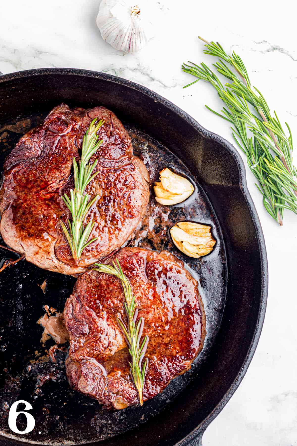 Delicious herb-crusted steaks cooked to perfection in a cast iron skillet with fresh rosemary and ga.