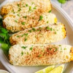 Delicious cornbread with lime wedges and cilantro on a white platter.