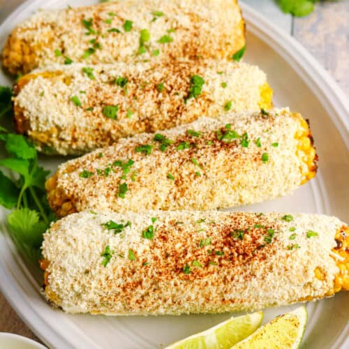 Delicious cornbread with lime wedges and cilantro on a white platter.
