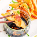 Easy Potstickers dipped in sauce on white plate