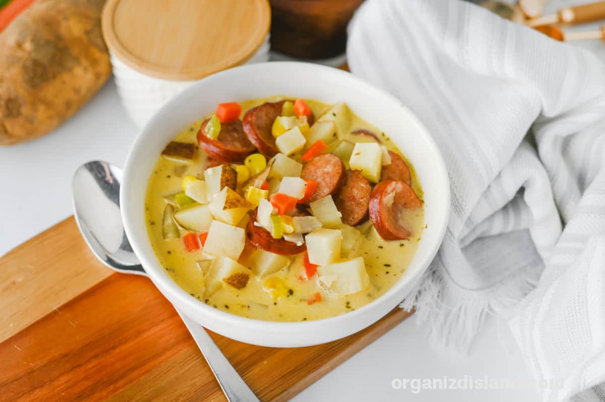 Warm bowl of sausage and potato soup with vegetables and herbs.
