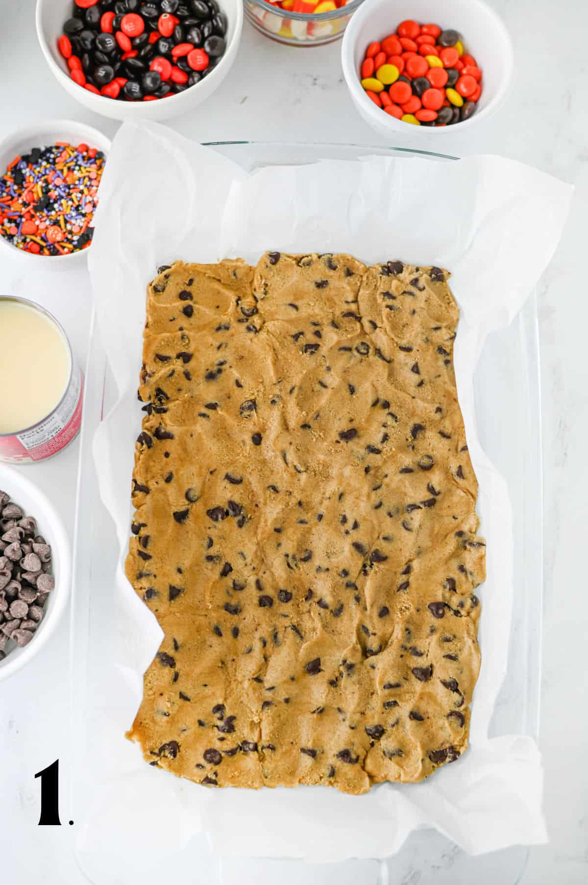 How to Make Halloween Cookie Bars Step 1 - pressing raw cookie dough in lined pan.