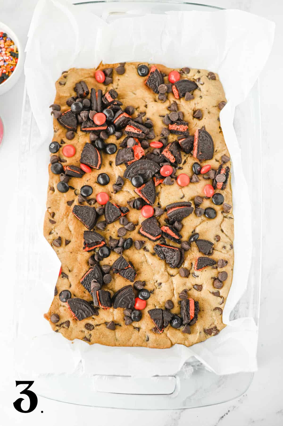 How to Make Halloween Cookie Bars Step 3 - pressing oreo pieces into dough.