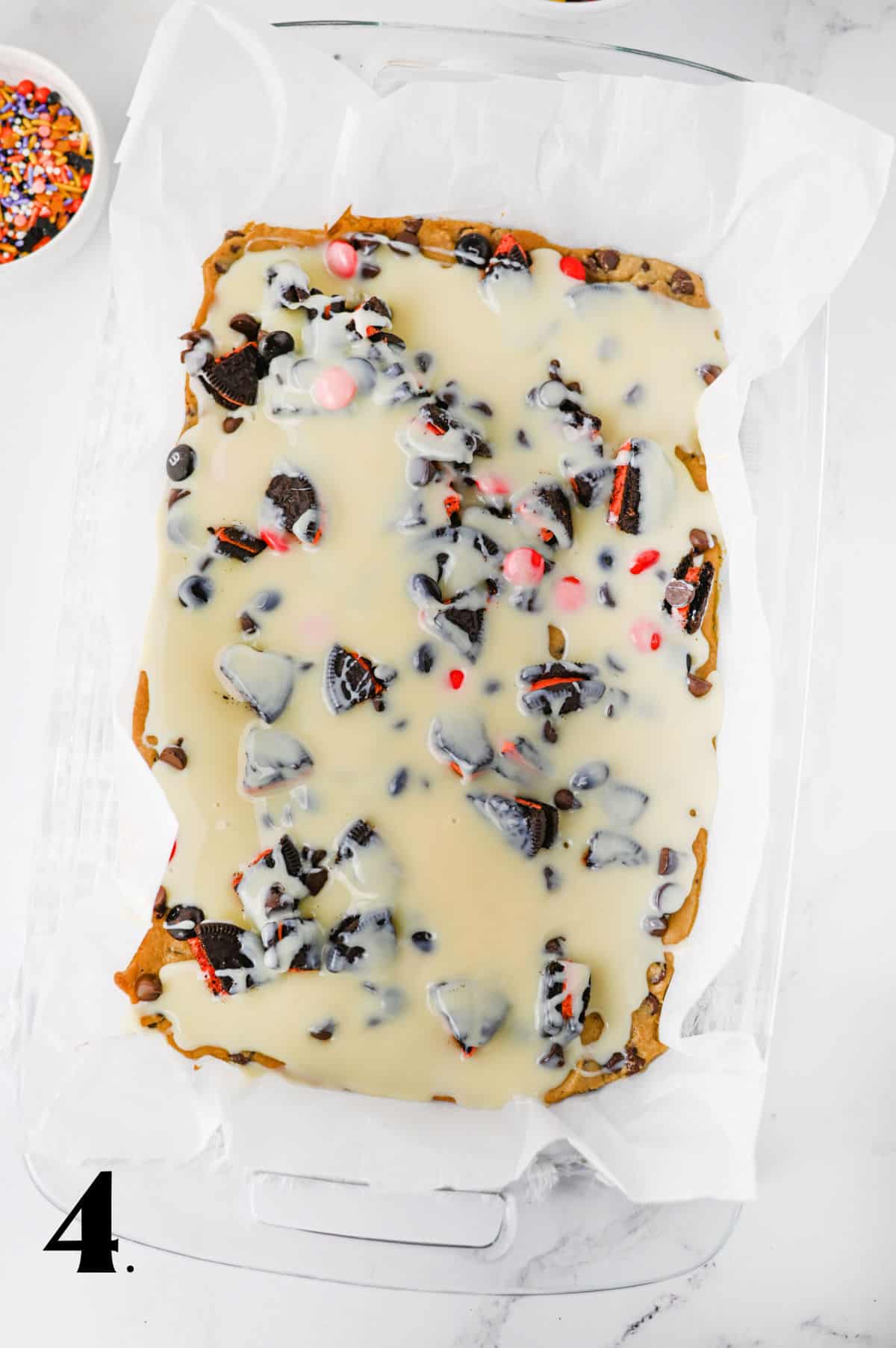 Festive Halloween cookie bark with candy, chocolate, and sprinkles on white background.