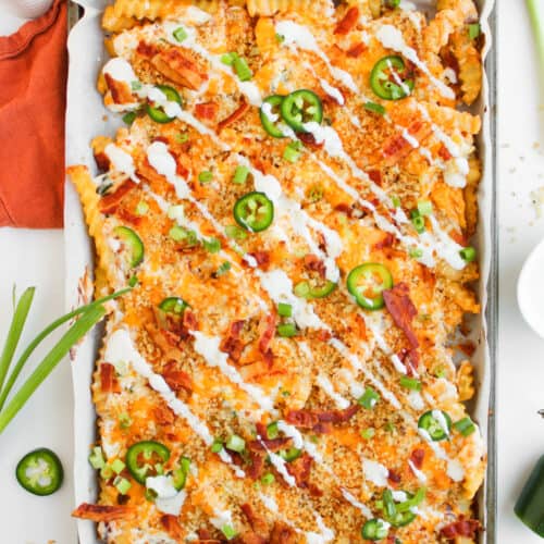 Loaded Fries with sour cream and cheese on sheet pan.