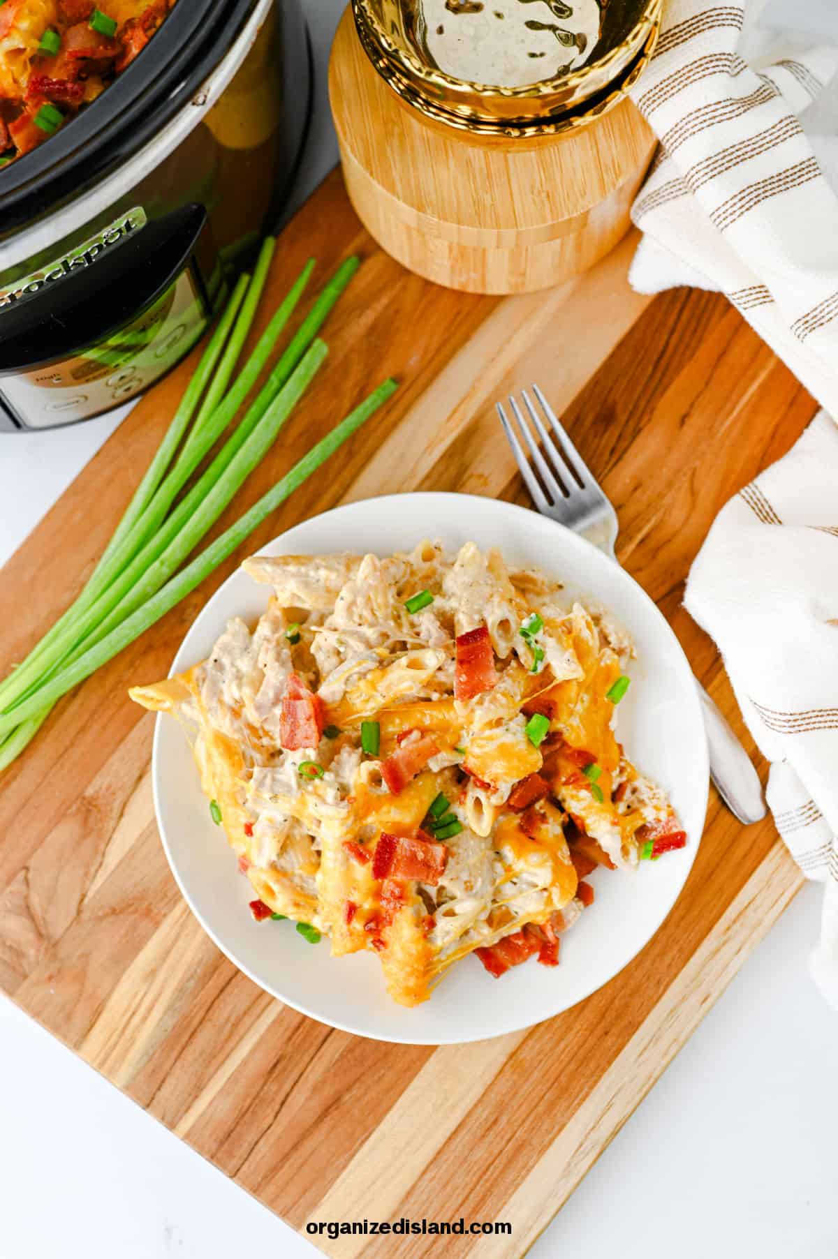 Crock Pot Crack Chicken Pasta on plate next to fork and onion.