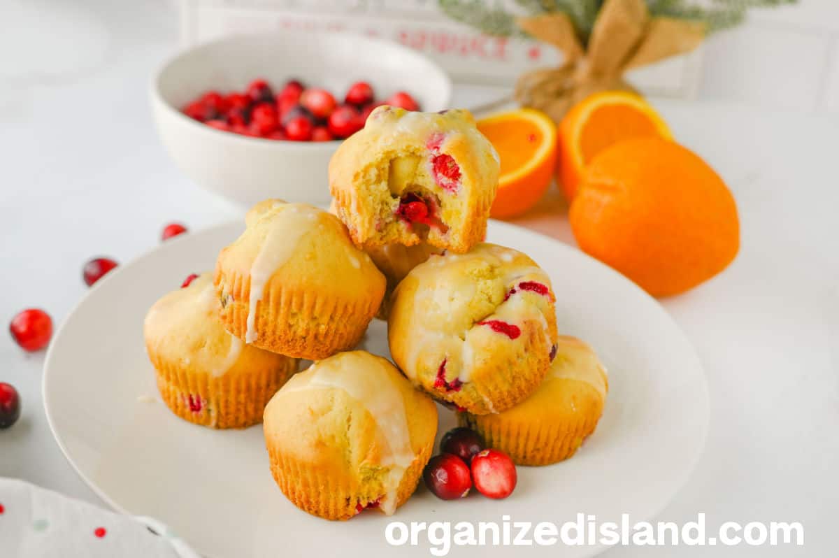 Best Cranberry Orange Muffins on plate with oranges nad cranberries in background.