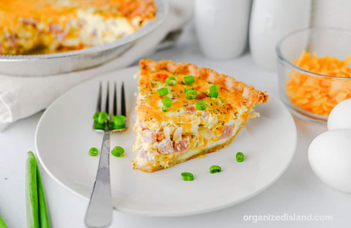 Best Ham and Cheese Quiche with green onions on top of slice.