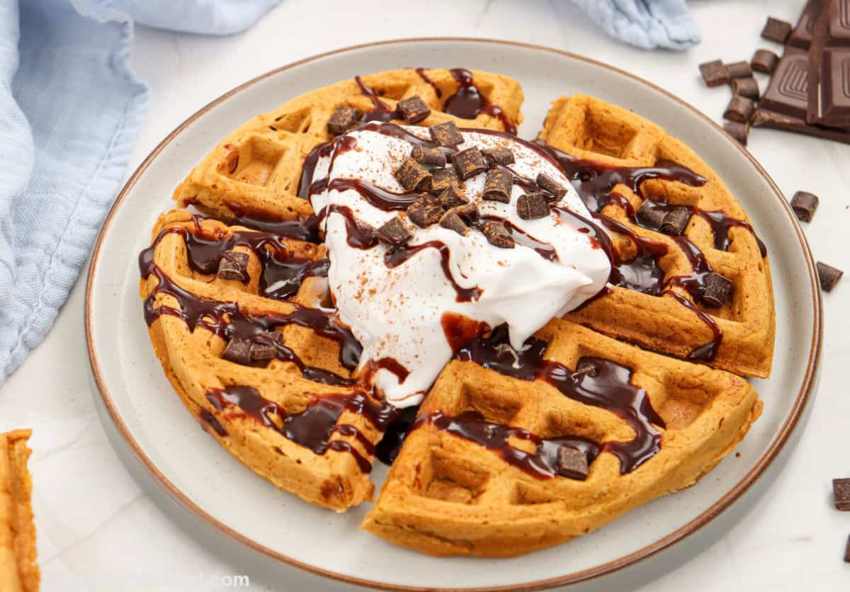 Best Pumpkin Waffles on plate with whipped cream and chocolate.