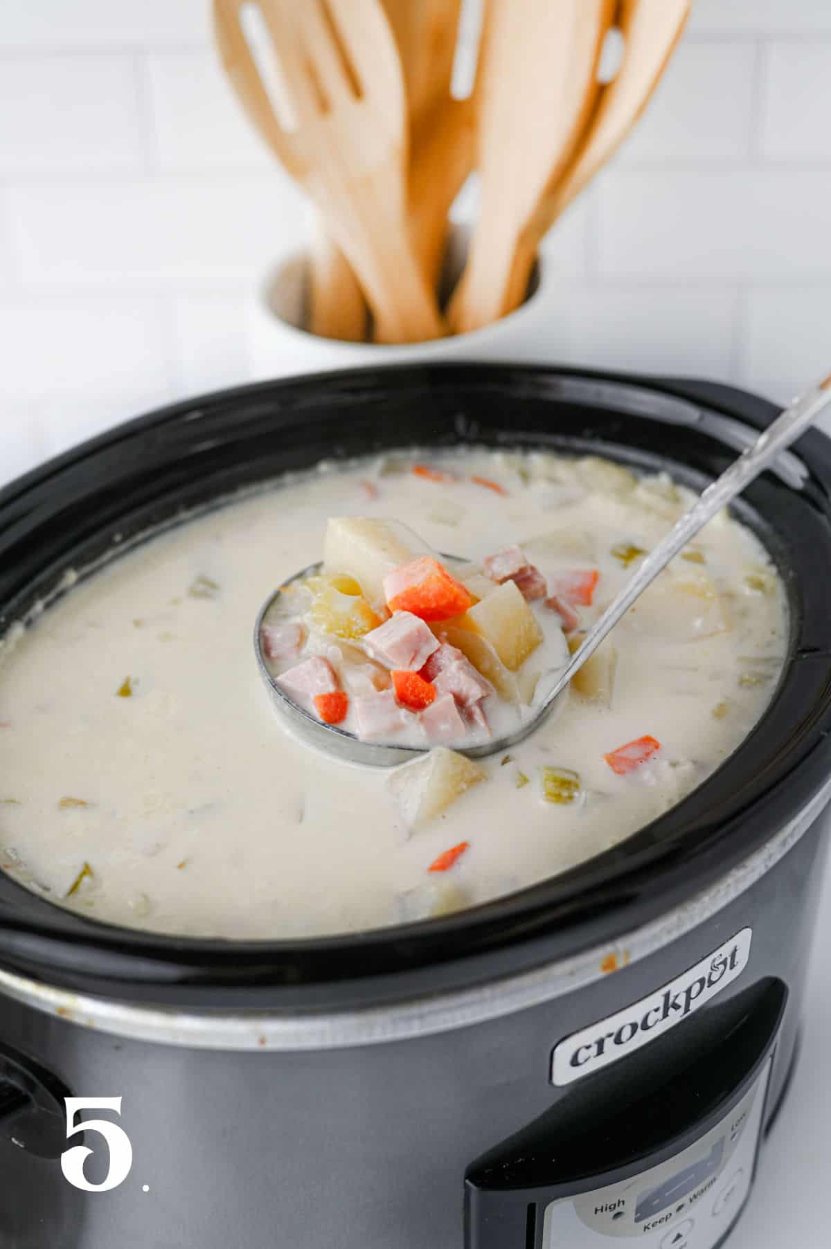 How to Make Slow Cooker Ham and Potato Soup Step 5 - using ladle to transfer soup out of crock pot.