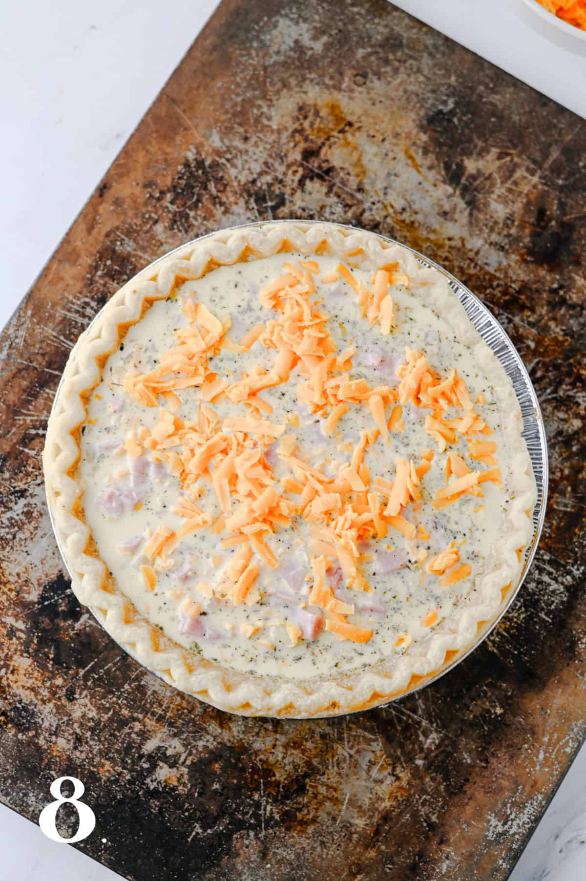 How to make a Ham and Cheese Quiche Step 8 - topped with cheese before baking.